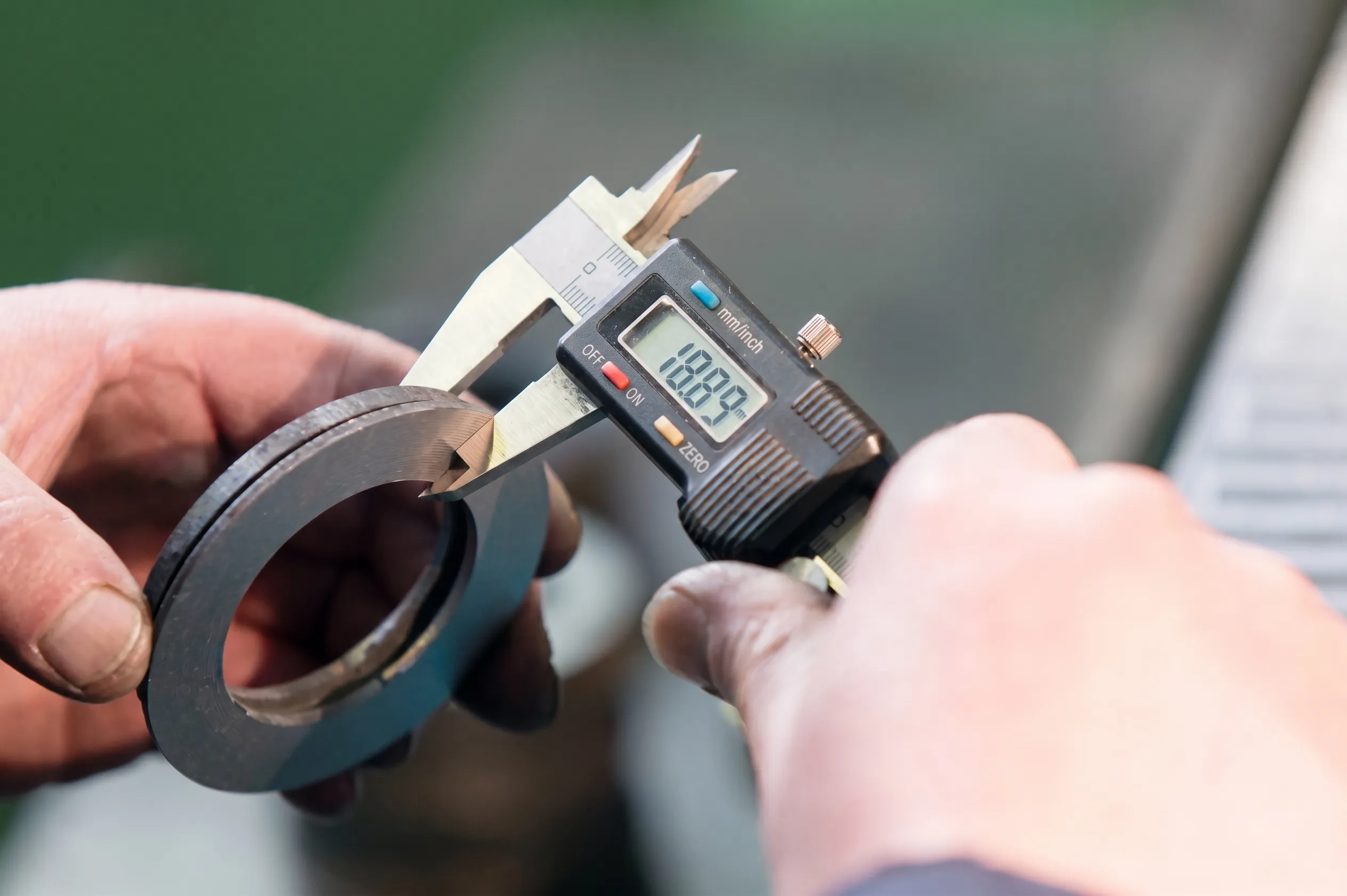 Operator measuring a machined part with calipers during dimensional inspection